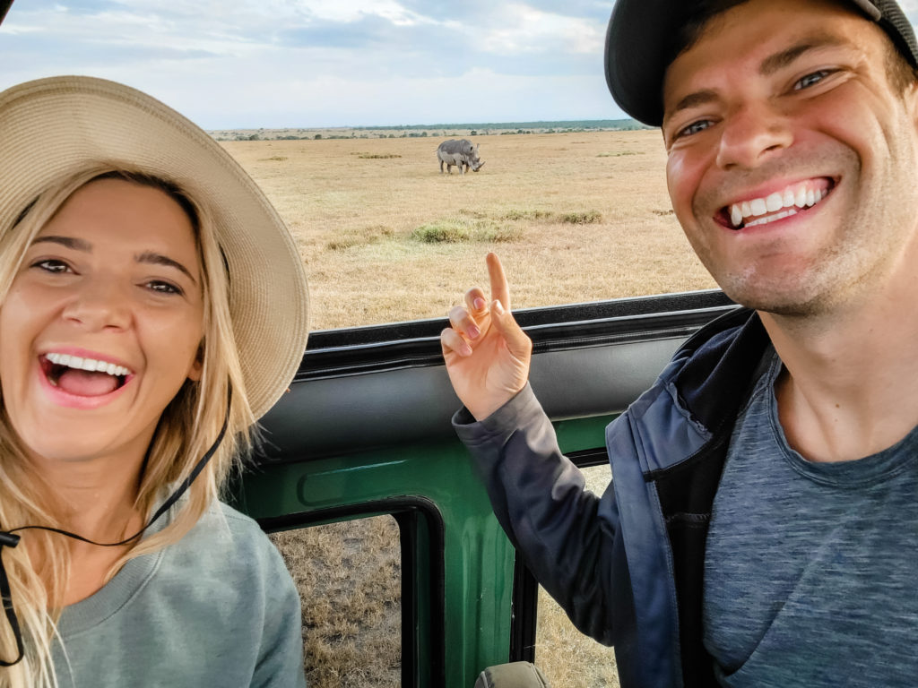 An image of a couple enjoying a safari watching a rhino in a landcruiser.